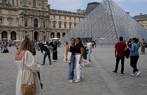 Tourists take pictures in front of the Pyramid in the Louvre Museum courtyard in Paris, France, on June 20, 2022.
