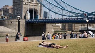 People are seen sunbathing at Tower Bridge area during the June heatwave.