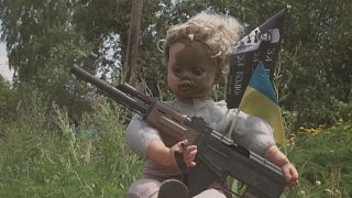 الصورة لدمية تمسك سلاحا في مدينة افديفكا الأوكرانية