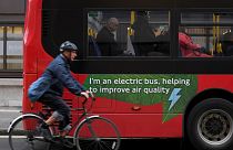 A cyclist rides past an electric public bus in London.