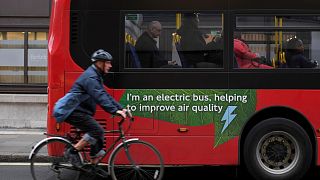 A cyclist rides past an electric public bus in London.