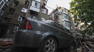 Los daños de un coche y un edificio de apartamentos se ven después del ataque ruso en una zona residencial en Sumy, Ucrania, lunes, 3 de julio de 2023.