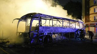 Feuerwehrleute setzen einen Wasserschlauch an einem brennenden Bus in Nanterre, außerhalb von Paris, Frankreich, ein, 1\. Juli 2023.