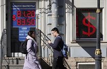 People walk past an exchange office screen showing the currency exchange rates of U.S. Dollar to Russian Rubles in St. Petersburg, Russia, Friday, April 7, 2023.