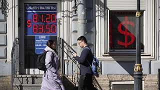 People walk past an exchange office screen showing the currency exchange rates of U.S. Dollar to Russian Rubles in St. Petersburg, Russia, Friday, April 7, 2023. 