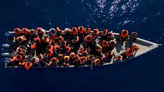 Migranten aus Eritrea, Libyen und dem Sudan segeln in einem Holzboot, bevor sie von Helfern der spanischen NRO Open Arms unterstützt werden