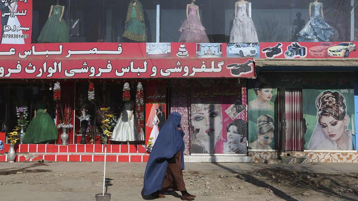 Afgán nő sétál Kabulban egy butik és egy szépségszalon előtt 2015-ben