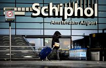 A women pulls a suitcase in high winds outside Schiphol airport, Amsterdam.