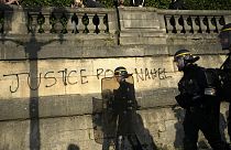 "Justiça por Nahel", lê-se em muro junto ao qual passa a polícia de intervenção para conter os protestos em França