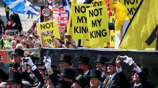 Anti-monarchy protesters hold placards near St Giles' Cathedral in Edinburgh as Charles III arrives for a coronation celebration