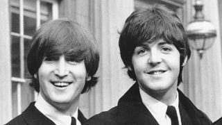 John Lennon, left, and Paul McCartney as they smile during a ceremony at Buckingham Palace in London, 1965