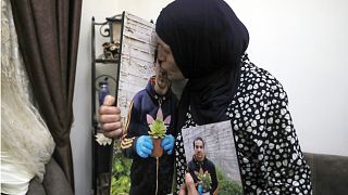 رنا، والدة إياد حلاق تقبل صورة ابنها في منزلهم في وادي الجوز