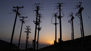 The sun sets behind electricity posts on the Aegean Sea island of Tilos, southeastern Greece, Monday, May 9, 2022. 