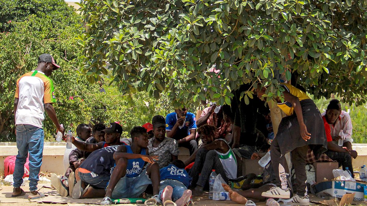 مهاجرون يحتمون بظل شجرة وسط مدينة صفاقس التونسية، خلال احتجاجهم على سوء أوضاعهم الإنسانية. 2023/07/07