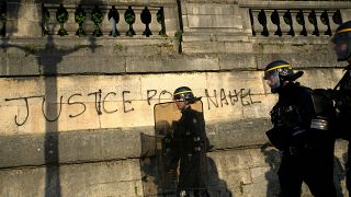 عناصر للشرطة الفرنسية تمر بجانب غرافيتي ينادي بالعدالة لنائل. 2023/06/30
