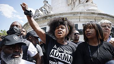 Woman raises her clenched fist in the air at the commemorative rally for Adama Traoré
