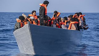  مهاجرون على ظهر قارب خشبي أثناء انتظارهم لتلقي المساعدة من قبل عمال الإغاثة من منظمة "أوبن آرمز"، في البحر الأبيض المتوسط، 17 يونيو 2023