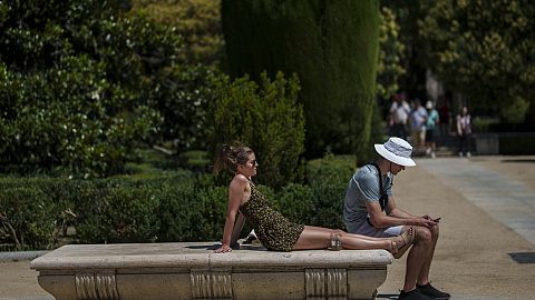 A couple rest in a park during a hot summer day in Madrid in July 2023.