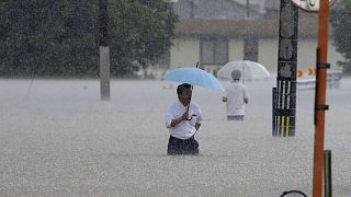 People wade through a street due to a heavy rain in Kurume, Fukuoka prefecture, southern Japan.