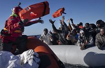 Migrantes y refugiados africanos que navegan a la deriva en una embarcación de goma abarrotada reciben chalecos salvavidas de los cooperantes de la ONG española Aita Mary en el mar Mediterráneo.