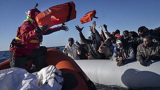 Migrants and refugees from Africa sailing adrift on an overcrowded rubber boat, receive life jackets from aid workers of the Spanish NGO Aita Mary in the Mediterranean Sea