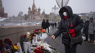 A woman wearing a medical mask lays flowers near the place where Russian opposition leader Boris Nemtsov was gunned down eight years ago, in Moscow.