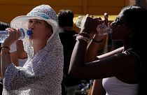 Turistas beben agua fría mientras se resguardan de una calurosa tarde soleada cerca del Coliseo de Roma, 5 de julio de 2023\. 