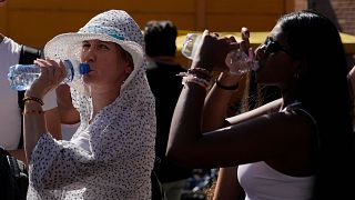 Turistas beben agua fría mientras se resguardan de una calurosa tarde soleada cerca del Coliseo de Roma, 5 de julio de 2023\.