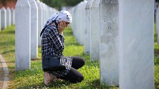 A Bosnian muslim woman mourns next to the grave of her relative, victim of the Srebrenica genocide, at the memorial centre in Potocari, Bosnia.
