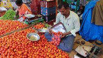 A vendor puts tomatoes in a single use plastic cover at a wholesale vegetable market in Hyderabad, India, 30 June 2022.