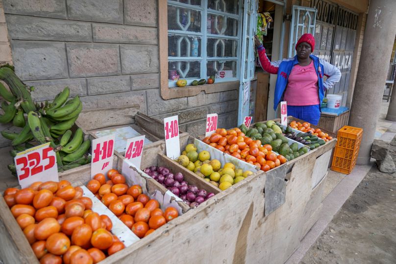 The owner of a small-scale shop selling vegetables stands by her produce in Kitengela, on the outskirts of the capital Nairobi, Kenya, Monday, April 17, 2023. 