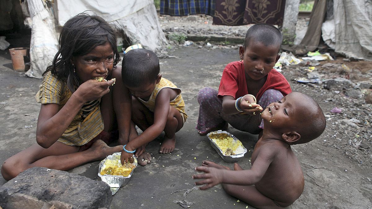 Indiai gyerekek eldobott ételmaradékokat esznek egy nyomornegyedben Gauhatiban 2013. július 4-én