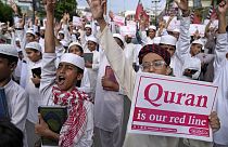 'Kuran bizim kırmızı çizgimiz' yazılı pankart taşıyan bir gösterici