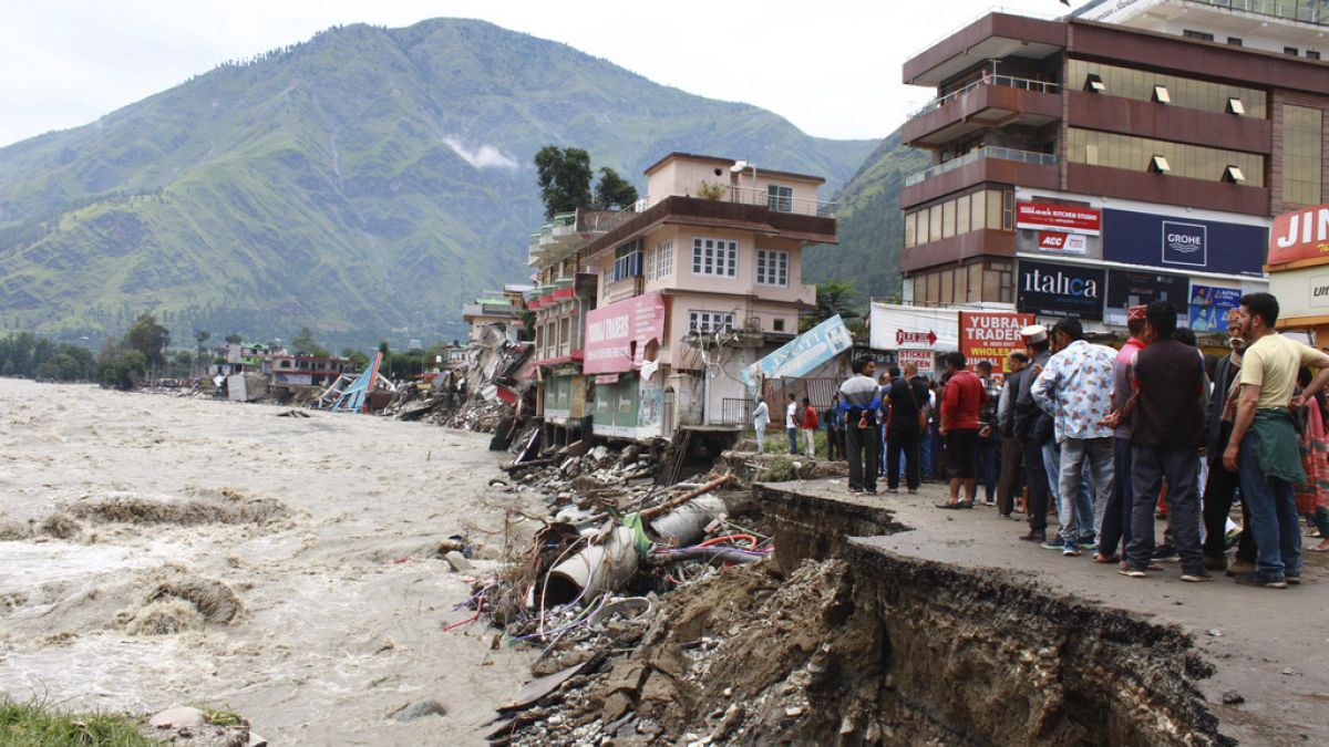Menschen stehen an einer Straße, die vom Fluss Beas weggespült wurde, der aufgrund starker Regenfälle im Distrikt Kullu im indischen Bundesstaat Himachal Pradesh gestiegen ist