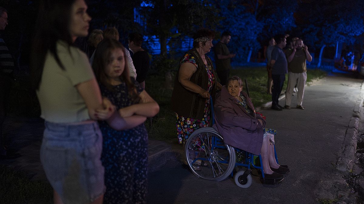 Residents stand outside an apartment building damaged in Russia's air attacks in Kyiv, Ukraine, Thursday, July 13, 2023.