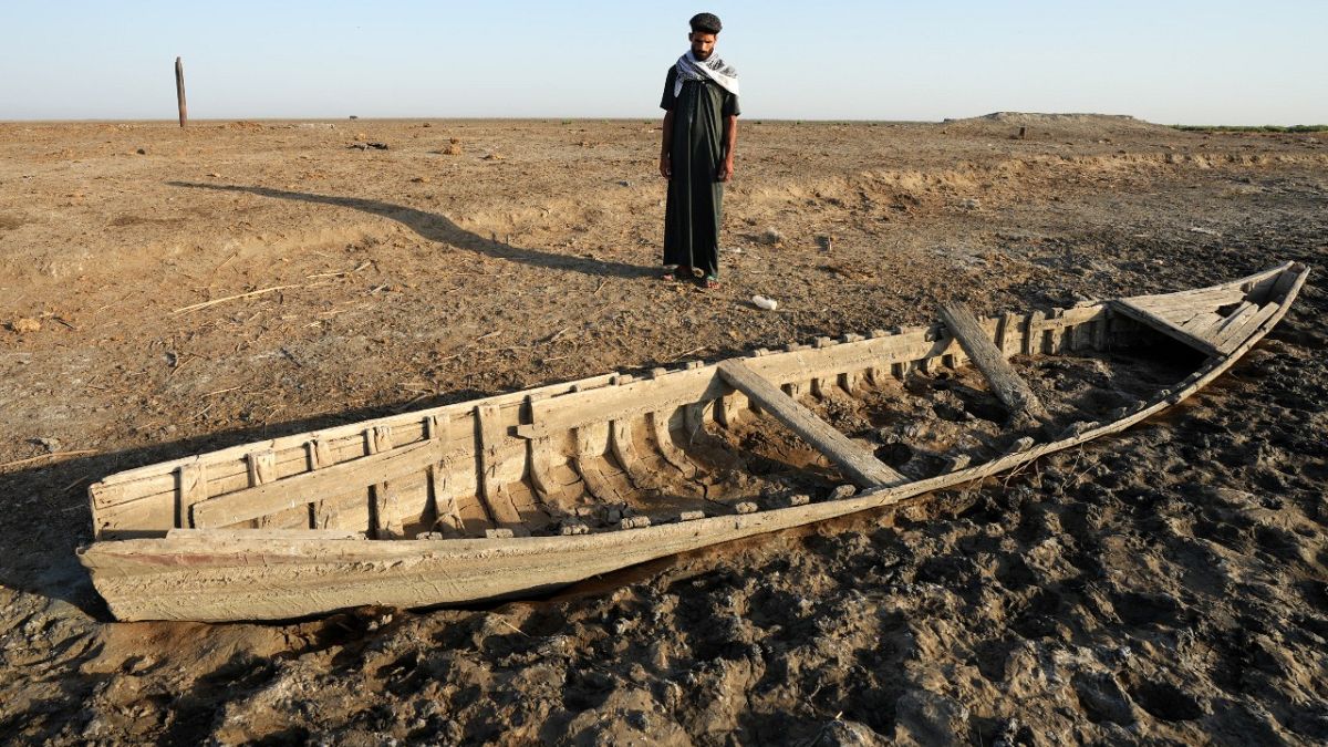 عراقي ينظر إلى زورق على طول ضفة جافة في أهوار الجبايش في جنوب العراق.