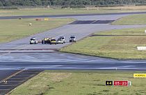 Security personnel and police officers stand near climate activists from the group Last Generation who stuck themselves to tarmac at Hamburg Airport, Germany, July 13, 2023.