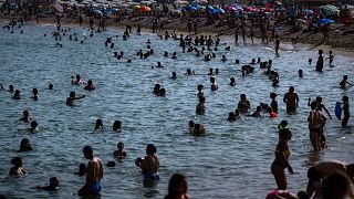 People cool off on a beach in Barcelona, Spain, 12 July 2023.