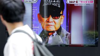 A passer-by watches a TV news reporting Johnny Kitagawa's passing away in Tokyo, on July 10, 2019.