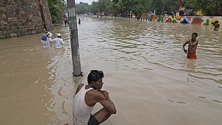 People wade through a flooded street in New Delhi