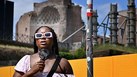 A woman cools off with a mini fan in Rome, on July 14, 2023, as Italy is hit by a heatwave.