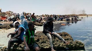 Migrantes subsarianos numa praia fronteiriça entre a Tunísia e a Líbia