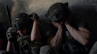 Ukrainische Soldaten halten sich die Ohren zu, um sich vor einem russischen Panzergeschoss an der Front im Gebiet Saporischschja zu schützen