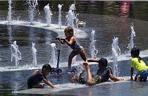 Niños de la ciudad intentan refrescarse en una fuente de agua en Grand Park, en el centro de Los Ángeles, el domingo 16 de julio de 2023.
