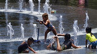 Niños de la ciudad intentan refrescarse en una fuente de agua en Grand Park, en el centro de Los Ángeles, el domingo 16 de julio de 2023.