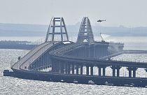A helicopter drops water to stop fire on Crimean Bridge connecting Russian mainland and Crimean peninsula over the Kerch Strait, in Kerch, on Oct. 8, 2022. 