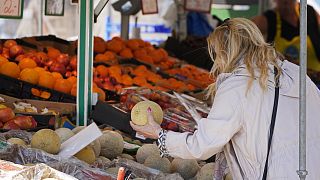 Женщина покупает фрукты на уличном рынке