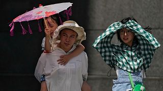 People walk on a street on a sweltering day in Beijing, 6 July 2023.