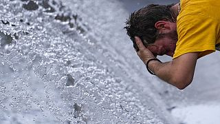 A man cools off at a fountain during a sunny day in Belgrade, Serbia