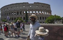 A street vendor walks with hats in front of the Colosseum in Rome